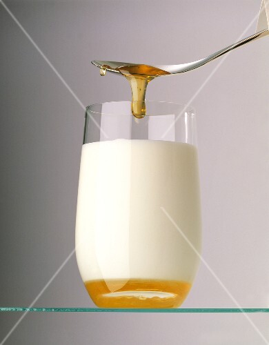 Honey running from a spoon into a glass of milk (1)