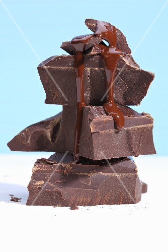 Liquid chocolate dripping down a stack of chocolate pieces