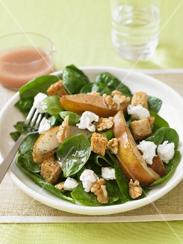 Spinach Salad with Pear Slices, Walnuts and Feta Cheese on a Plate with Fork