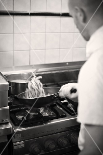 Koch bereitet das Essen in einer Pfanne