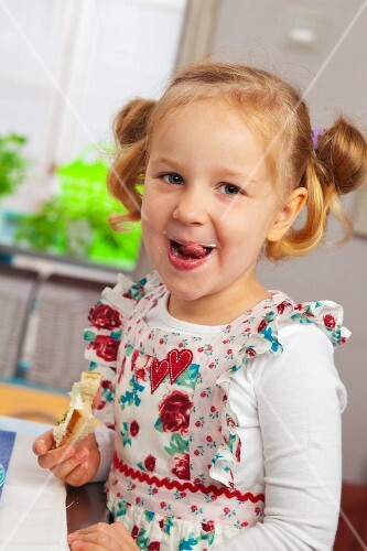 Little girl eating bread with cottage cheese and cress