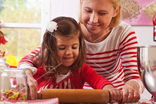 Mutter und Tochter rollen Teig aus