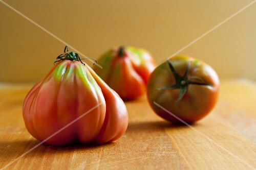 Three Fresh Ugly Tomatoes on Wooden Surface