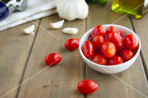 Grape Tomatoes and Garlic Cloves on a Wooden Table