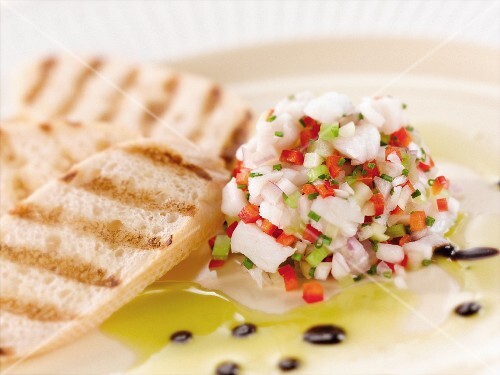 Citrus Ceviche of Bass Fish with Grilled Bread on a White Plate