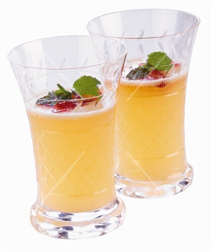 Two Glasses of Banana Slush Punch garnished with Raspberries and Mint