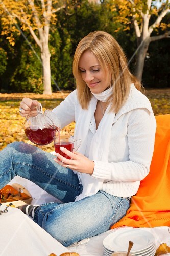 Woman pouring fruit tea at autumn picnic