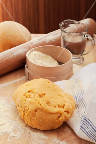 Pasta dough, a flour sieve, a wooden spoon and water