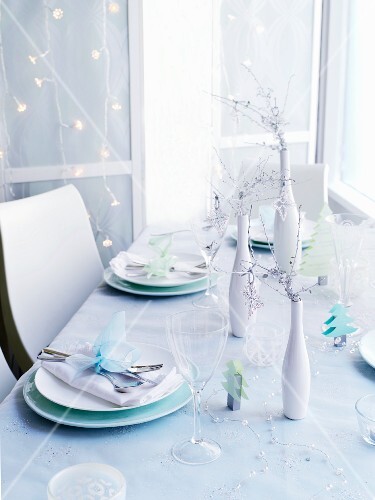 A table laid for Christmas in front of a wall hung with a chain of lights