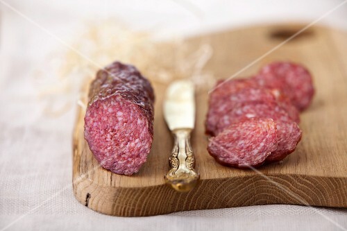 Salami, partially sliced, on a chopping board