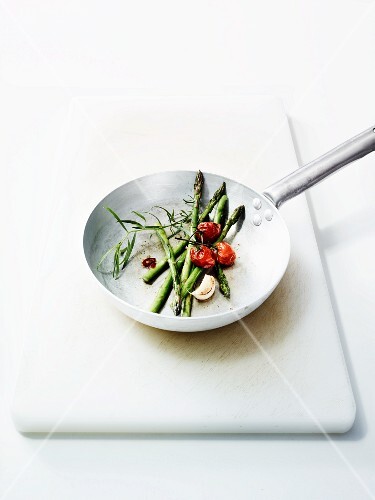Green asparagus with cherry tomatoes and garlic in a pan