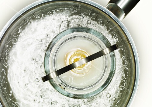 An egg in a jar in a pot of boiling water
