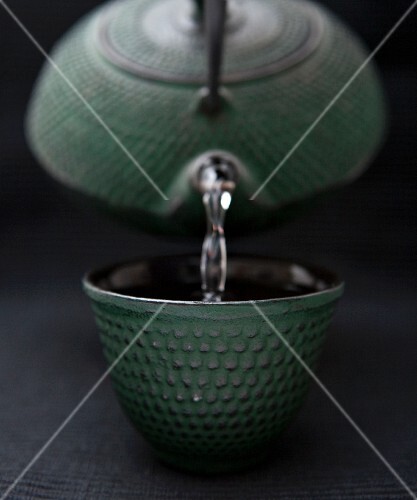 Jasmine Green Tea Pouring From a Green Cast Iron Tea Pot Into a Green Cast Iron Tea Cup
