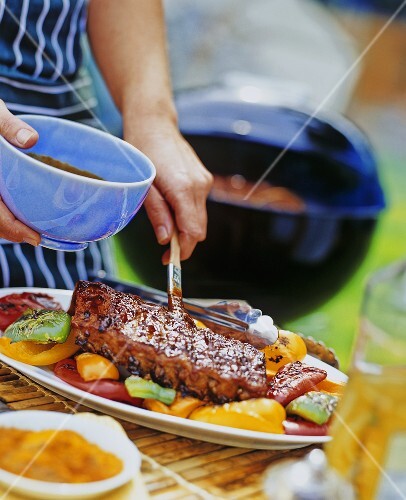 Gegrillte Spareribs mit Grillsauce bepinseln