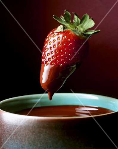 Strawberry being dipped in chocolate fondue