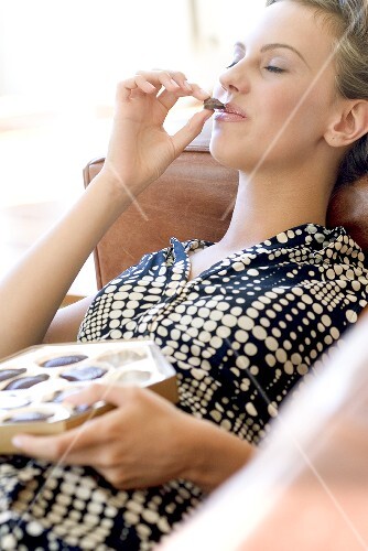 Young woman about to put a chocolate in her mouth