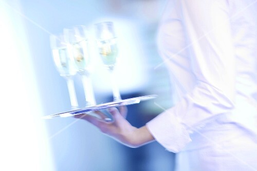 Waitress carrying tray of champagne glasses