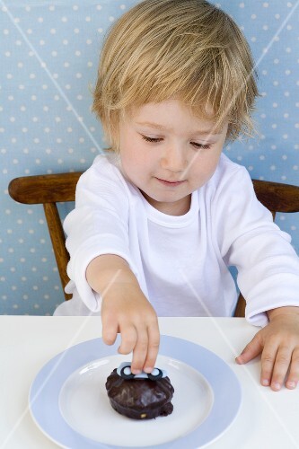Kleiner Junge greift nach einem kleinen Schokoladenkuchen