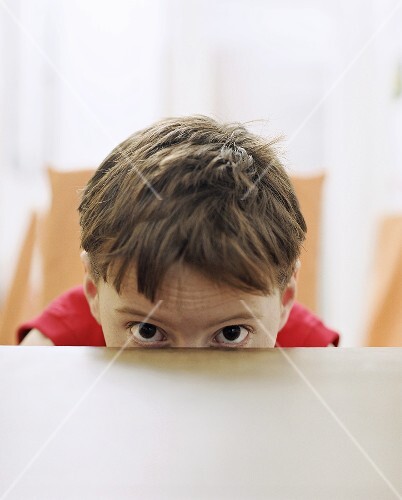 Boy hiding behind table