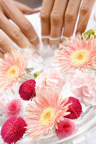 Young woman bathing her hands in a bowl of water with flowers