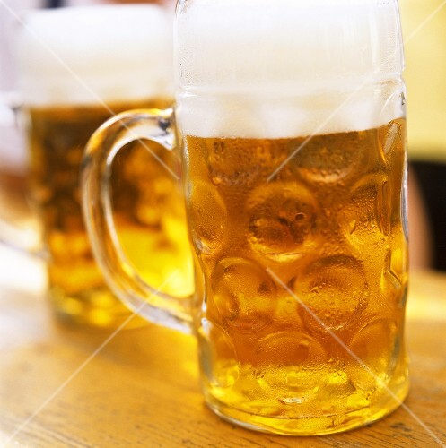 Two tankards of cold beer on a wooden table