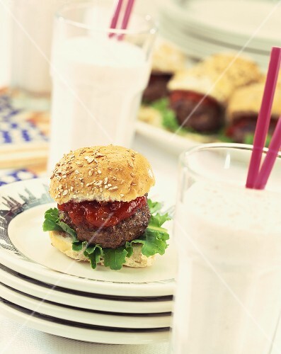Mini-hamburger with ketchup on pile of plates