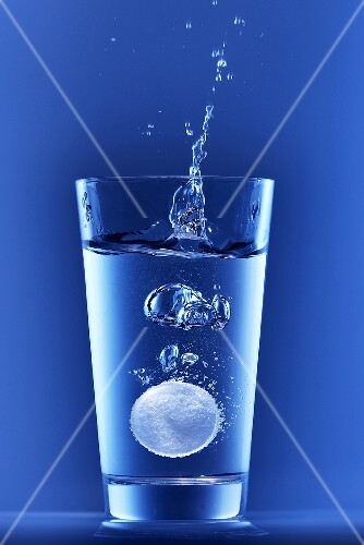 Effervescent tablet falling into a glass of water