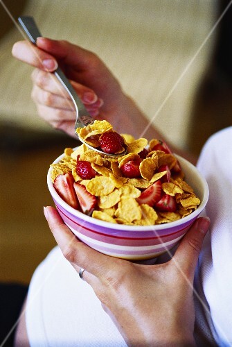 Pregnant woman eating cornflakes with strawberries
