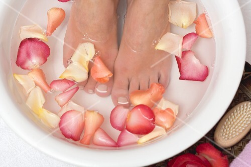 Woman bathing her feet in rose petal water