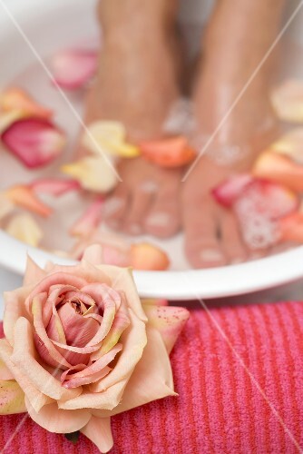 Woman bathing her feet in rose petal water