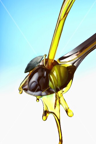 Pouring olive oil over olives on spoon