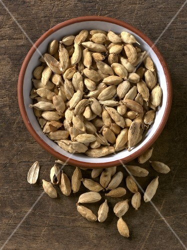 Cardamom pods in and beside bowl