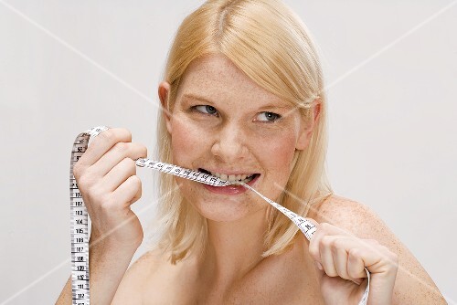 Blond woman biting tape measure