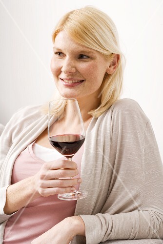 Blond woman holding glass of red wine