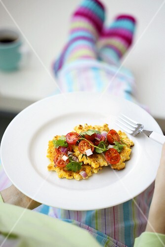 Person holding plate of corn cakes and salsa