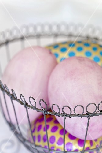 Coloured eggs, pink and spotted, in a wire basket