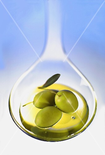 Olive oil and three olives in a spoon