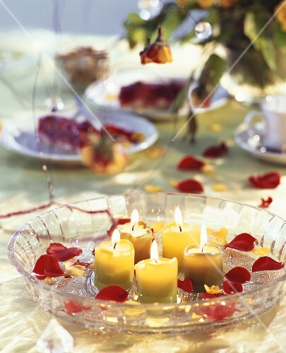 Bowl of water with candles and rose petals