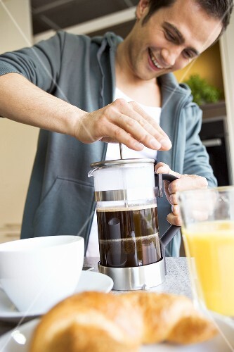 Mann macht Kaffee in einem Kaffeebereiter