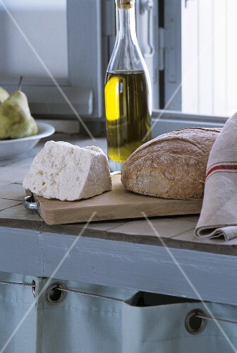 Loaf of bread and cheese on a wooden board with olive oil