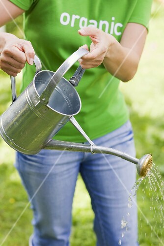 A woman with a watering can in a garden