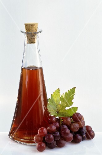A bottle of grape vinegar with fresh grapes