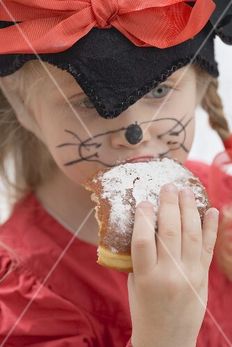 Girl in fancy dress biting into a doughnut (Carnival)
