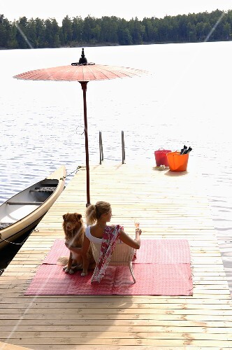 Woman with glass of strawberry Prosecco & dog on landing stage