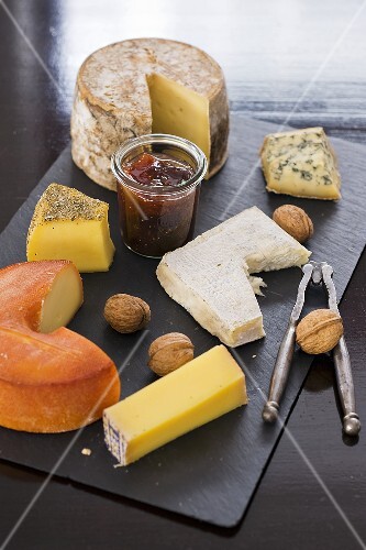 A cheese platter with nuts and jam