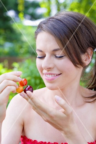 Young woman holding sweet cherries in her hand