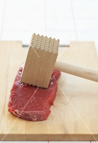 Rindfleisch mit Fleischklopfer auf Schneidebrett