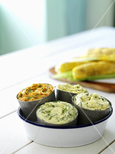 Assorted herb and spice butters, corn on the cob behind