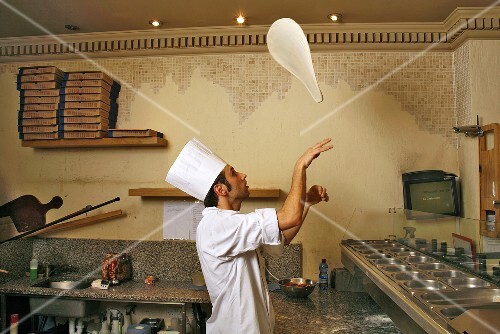 Italian pizza baker throwing dough into the air
