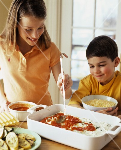 Girl and boy making vegetable lasagne together